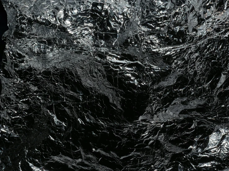 a black and white photo of a piece of foil, an album cover, inspired by Andreas Gursky, unsplash, abstract expressionism, high resolution coal texture, black slime, hyper realistic 8 k textured, ignant