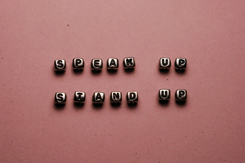 the words speak up stand up on a pink surface, trending on pexels, studs, brown, false teeth, blocks