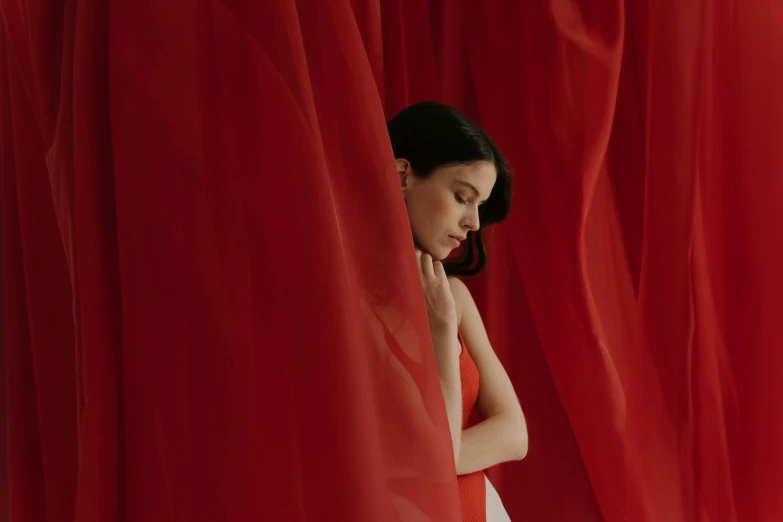 a woman standing in front of a red curtain, by Emma Andijewska, pexels contest winner, sheer fabrics, cindy avelino, instagram post, in style of cecil beaton