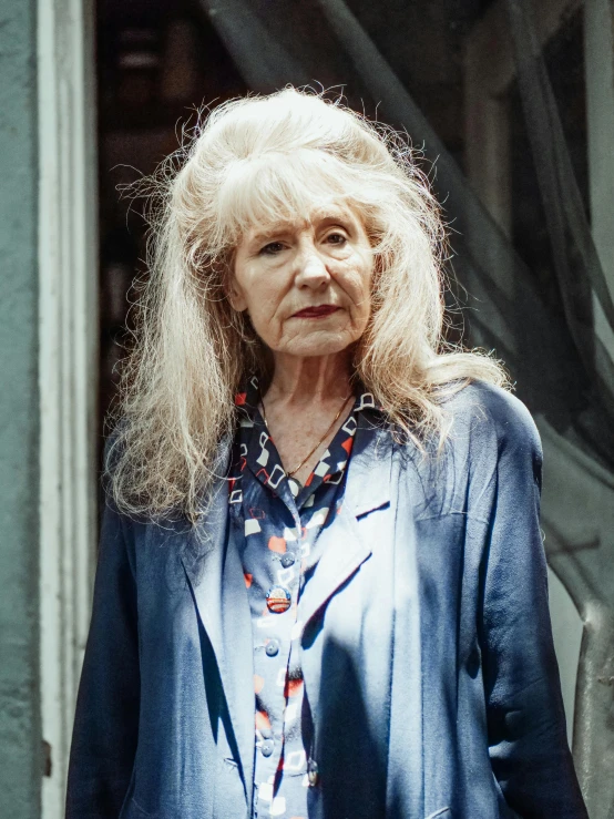 a woman standing in front of a door, by Helen Biggar, photorealism, disheveled, 2022 photograph, older woman, wearing a blue jacket