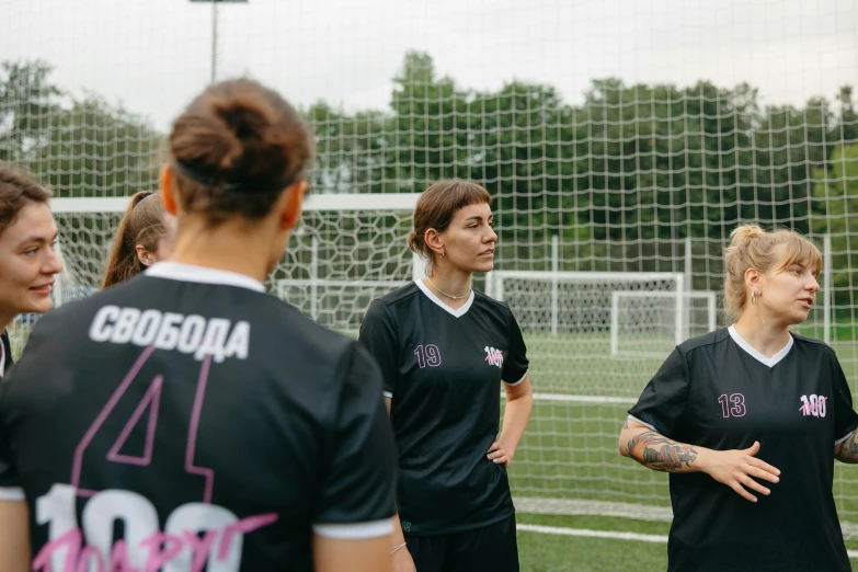 a group of women standing on top of a soccer field, unsplash, private press, calmly conversing 8k, igor berezovsky, black jersey, pink tigers