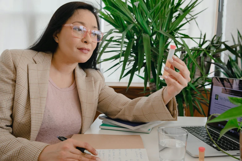 a woman sitting at a desk with a cell phone in her hand, pexels contest winner, holding syringe, asian descent, avatar image, studious