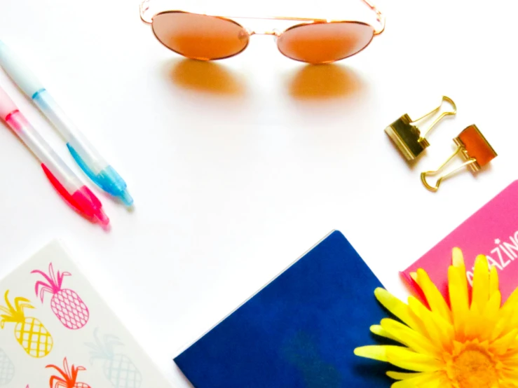 a yellow flower sitting on top of a white table, with sunglasses, various items, thumbnail, pink and blue colour