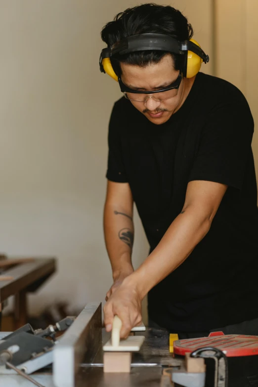 a man using a table saw to cut a piece of wood, a portrait, pexels contest winner, asian male, avatar image, grainy, made of wood