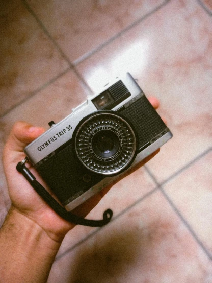 a person holding a camera on a tiled floor, by Alejandro Obregón, unsplash, photorealism, a photo of an old opened camera, \!cinestill 50d! film photo, instagram picture, canon a1