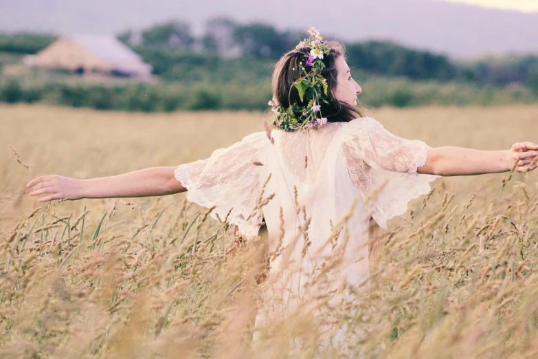 a woman standing in a field of tall grass, unsplash, romanticism, dressed in laurel wreath, arms stretched out, cottage hippie naturalist, clothes made out of flower