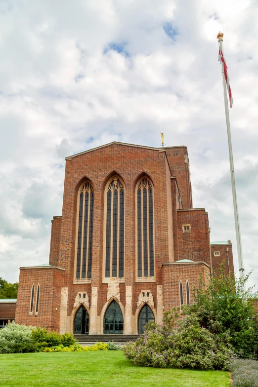 a large brick building sitting on top of a lush green field, an album cover, by Charles Uzzell-Edwards, unsplash, modernism, cathedral, elevation view, barnet, alvar aalto