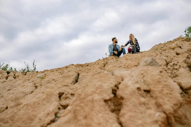 a couple of people sitting on top of a hill, by Adam Marczyński, pexels contest winner, cracked earth, low shot angle, profile image, picnic