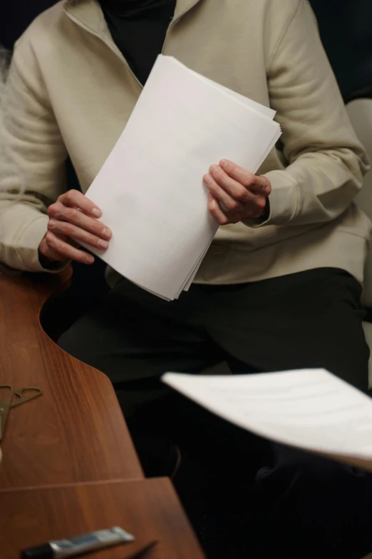 a man sitting in a chair holding a piece of paper, ap news, courtroom the bench, taken in the late 2010s, manuscript