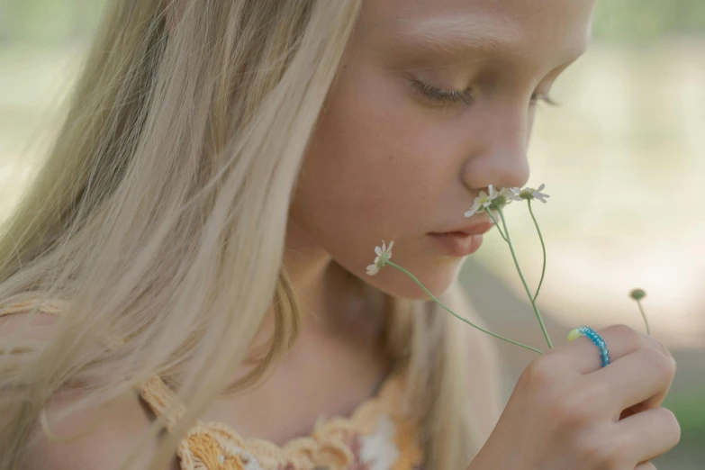 a little girl holding a flower in her hand, pexels contest winner, close up of a blonde woman, soft light.4k, shot with a arriflex 35 ii, cottagecore hippie