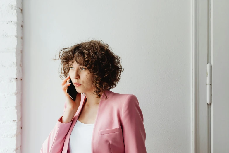 a woman in a pink jacket talking on a cell phone, by Matthias Weischer, trending on pexels, renaissance, brown curly hair, office clothes, with a white background, ekaterina