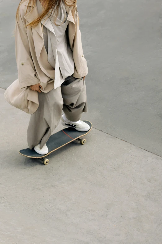 a woman riding a skateboard at a skate park, trending on unsplash, hyperrealism, tan suit, wearing a grey robe, large pants, muted colors with minimalism