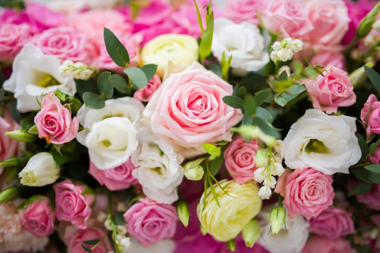 a bouquet of pink and white flowers on a table, zoomed in, upclose, full of colour, laying on roses