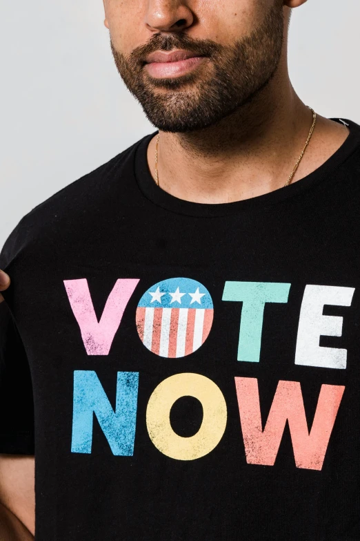 a man wearing a t - shirt that says vote now, inspired by Milton Glaser, detail shot, pr shoot, modeling shoot, lgbt