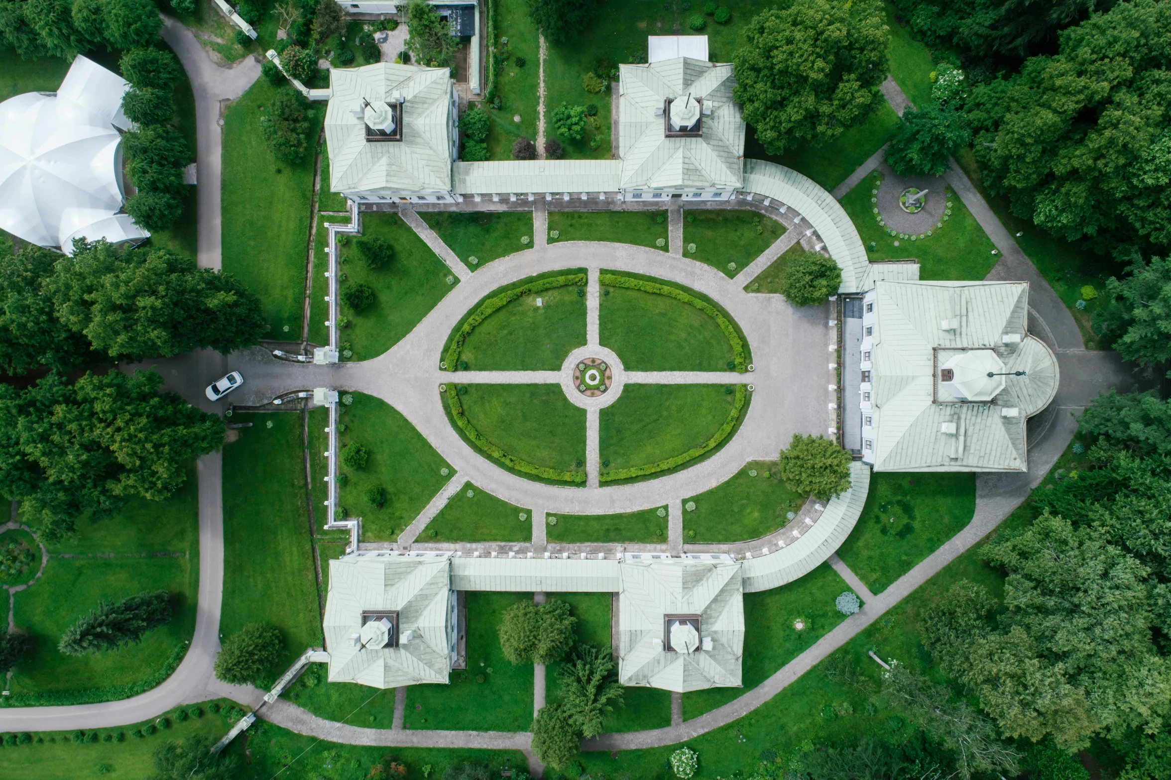 an aerial view of a mansion surrounded by trees, an album cover, by Attila Meszlenyi, pexels contest winner, visual art, white stone arches, lawn, pentagon, a green