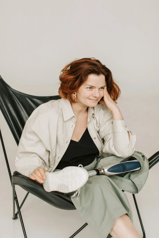 a woman sitting in a chair talking on a cell phone, by Grytė Pintukaitė, trending on unsplash, renaissance, casual pose, wearing a baggy, relaxing and smiling at camera, sitting in front of a microphone