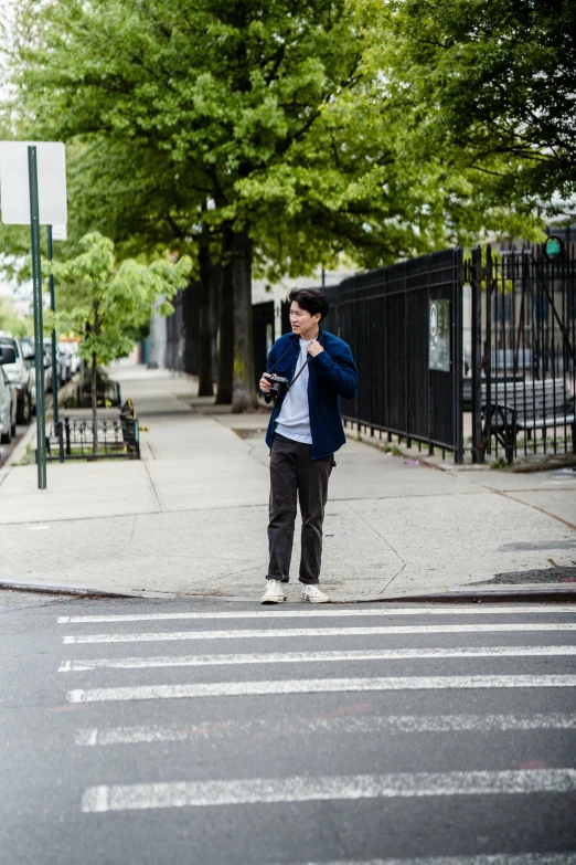 a man walking across a street while talking on a cell phone, by Nina Hamnett, unsplash, visual art, finn wolfhard, brooklyn, asian male, standing on street corner