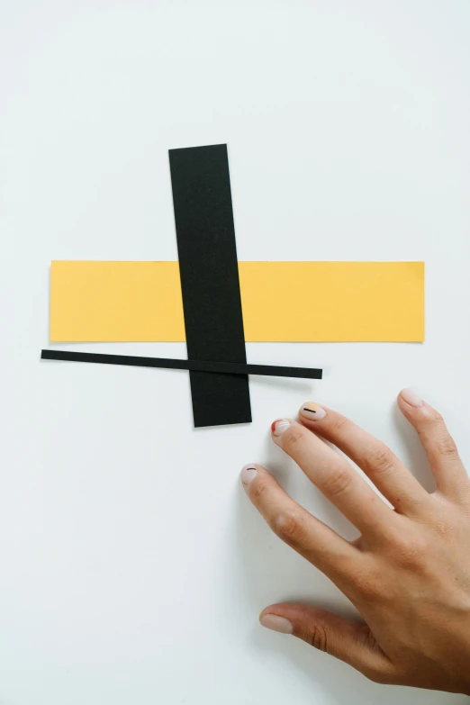 a close up of a person's hand near a clock, an abstract sculpture, inspired by László Moholy-Nagy, unsplash, suprematism, yellow and charcoal, assembly instructions, single long stick, made from paper