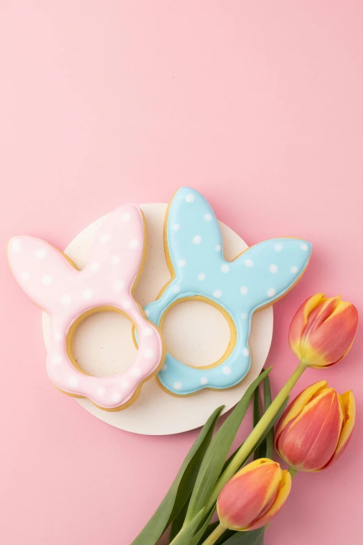 a plate of cookies and tulips on a pink background, with bunny ears, dotting, bangles, pearlized