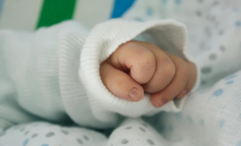 a close up of a baby's hand on a blanket, by Julian Allen, pexels, white sleeves, thumb up, serious business, coloured