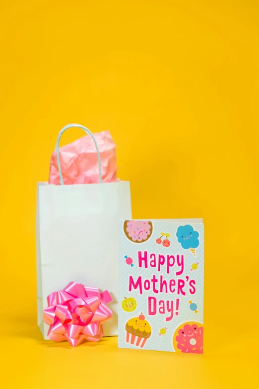 a mother's day card and gift bag on a yellow background, gogo : :, 360, front facing shot, tastes