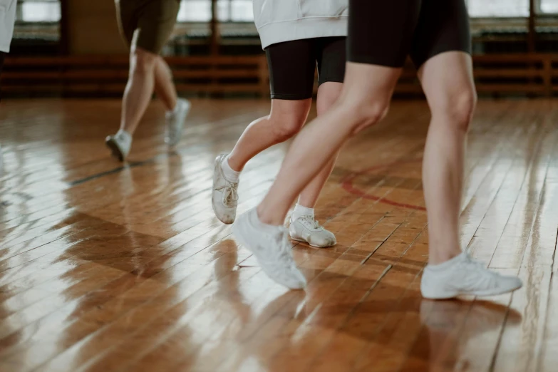 a group of people standing on top of a wooden floor, arabesque, wearing white sneakers, dribbling, zoomed in, local gym