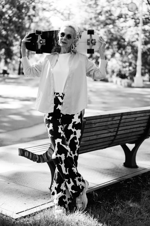 a black and white photo of a woman holding a skateboard, a black and white photo, campy. cow costume with udders, in a city park, high fashion photoshoot, 5 5 yo