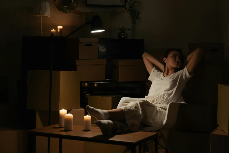 a woman sitting on a table with candles in front of her, no lights in bedroom, cinematic aura lighting, relaxing on a couch, gurney with ambient lighting