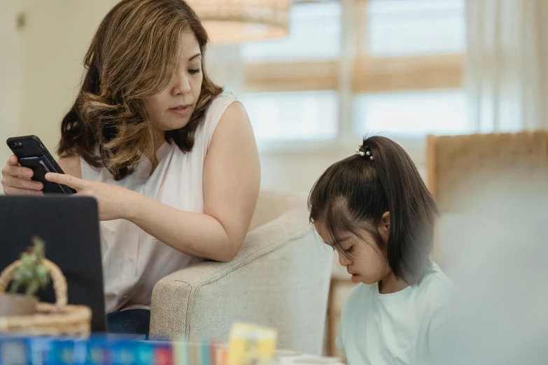 a woman sitting on a couch next to a little girl, by Natasha Tan, pexels contest winner, trying to study, looking her shoulder, idealised, walking down