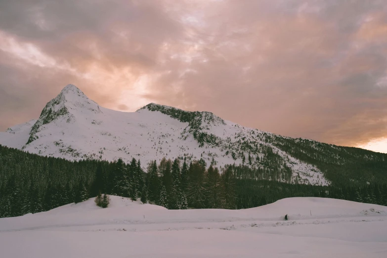 a mountain covered in snow next to a forest, pink skies, low quality photo, fan favorite, switzerland