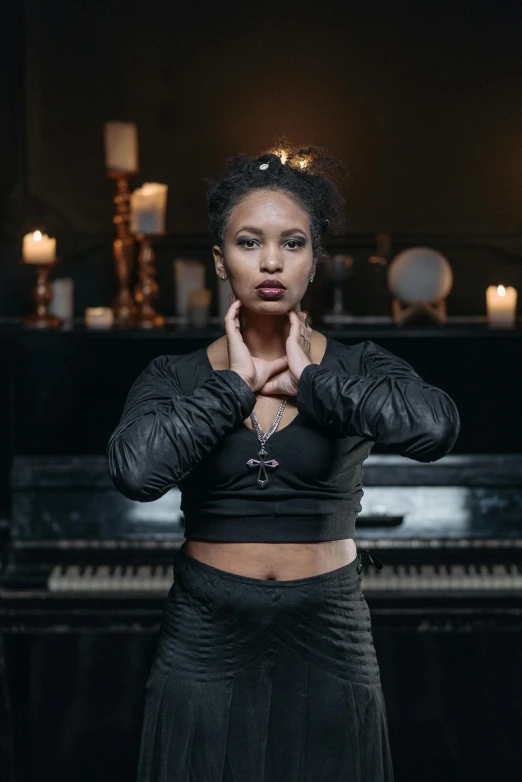 a woman standing in front of a piano, inspired by Sophia Beale, unsplash, black arts movement, in a leather corset, candlelit, arms out, photograph of a techwear woman