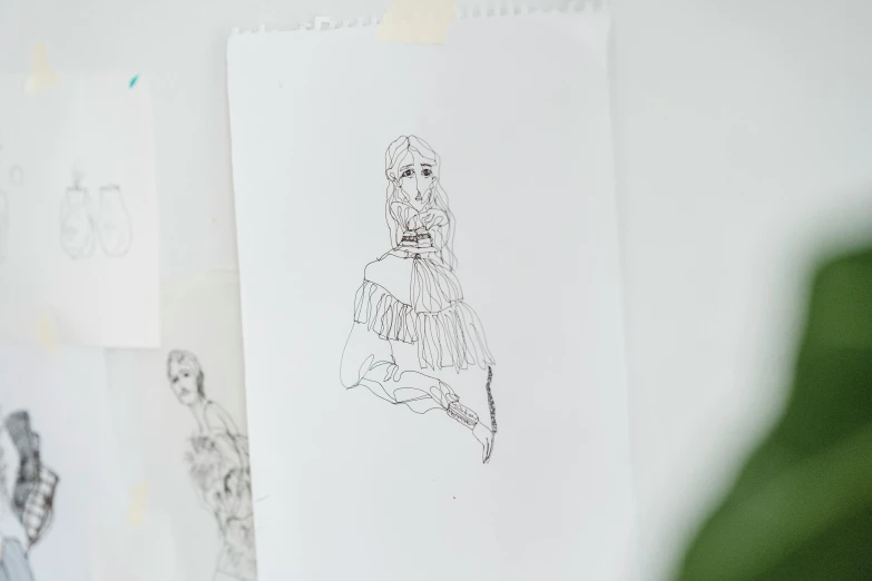 a bunch of drawings hanging on a wall, an ink drawing, by Emma Andijewska, serial art, art nouveau fashion embroidered, dainty figure, frill, portrait image