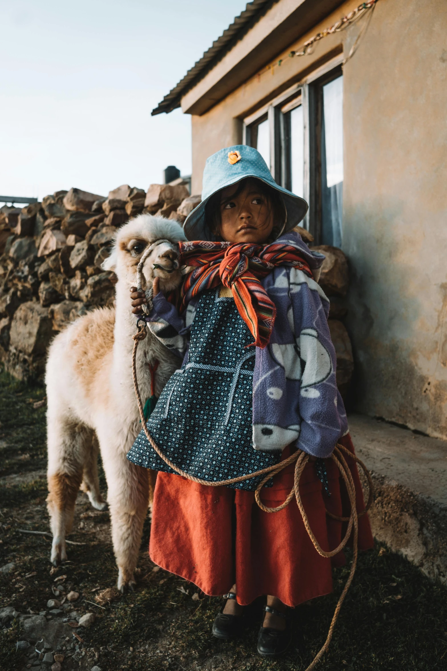 a woman standing next to a llama in front of a building, inspired by Steve McCurry, unsplash contest winner, little kid, farming, quechua, portrait of small