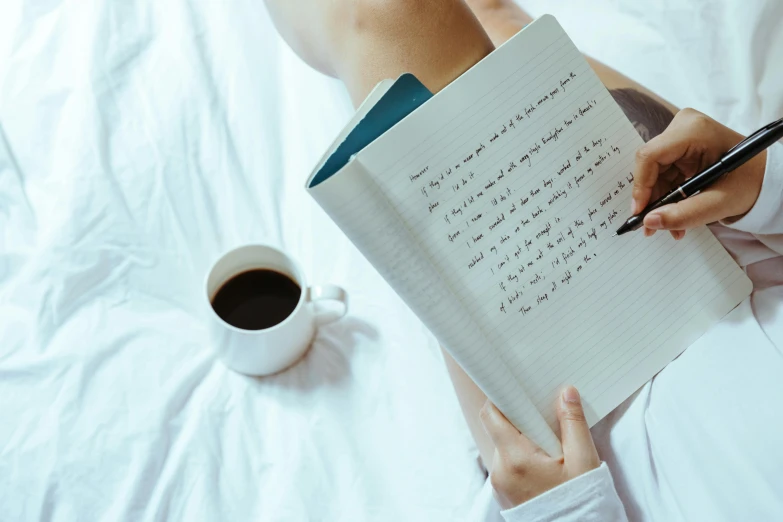 a woman sitting on top of a bed next to a cup of coffee, by Julia Pishtar, pexels contest winner, with some hand written letters, notebook, thumbnail, black