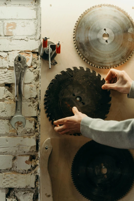 a man using a circular saw to cut a piece of wood, an album cover, pexels contest winner, kinetic art, ((gears)), taken with kodak portra, vertical orientation, hands