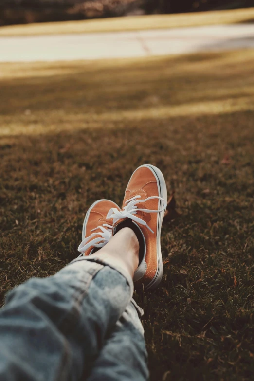 a person sitting in the grass with their feet up, by Eglon van der Neer, pexels contest winner, realism, orange grey white, sneaker shoes, warm hue, peaceful day