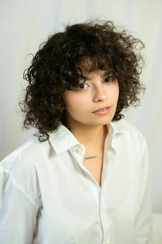 a woman with curly hair wearing a white shirt, an album cover, trending on pexels, photorealism, charli bowater, shot in the photo studio, middle eastern, taken with sony alpha 9