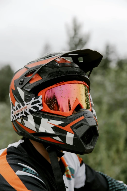 a close up of a person wearing a helmet and goggles, motocross bike, dark grey and orange colours, camo, reflective visor