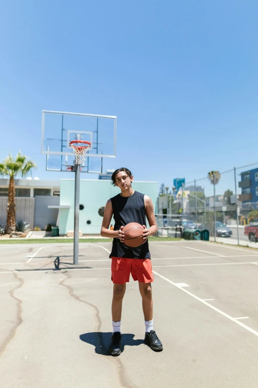 a man standing in a parking lot holding a basketball, by Gavin Hamilton, avan jogia angel, 15081959 21121991 01012000 4k, portrait size, dunking