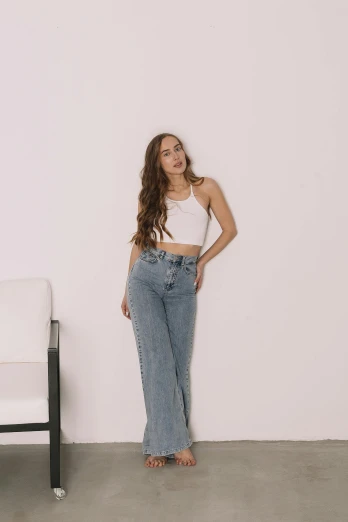 a woman standing in front of a white chair, inspired by Jean Hey, trending on pexels, renaissance, wearing crop top, ( ( ( wearing jeans ) ) ), portrait sophie mudd, instagram post