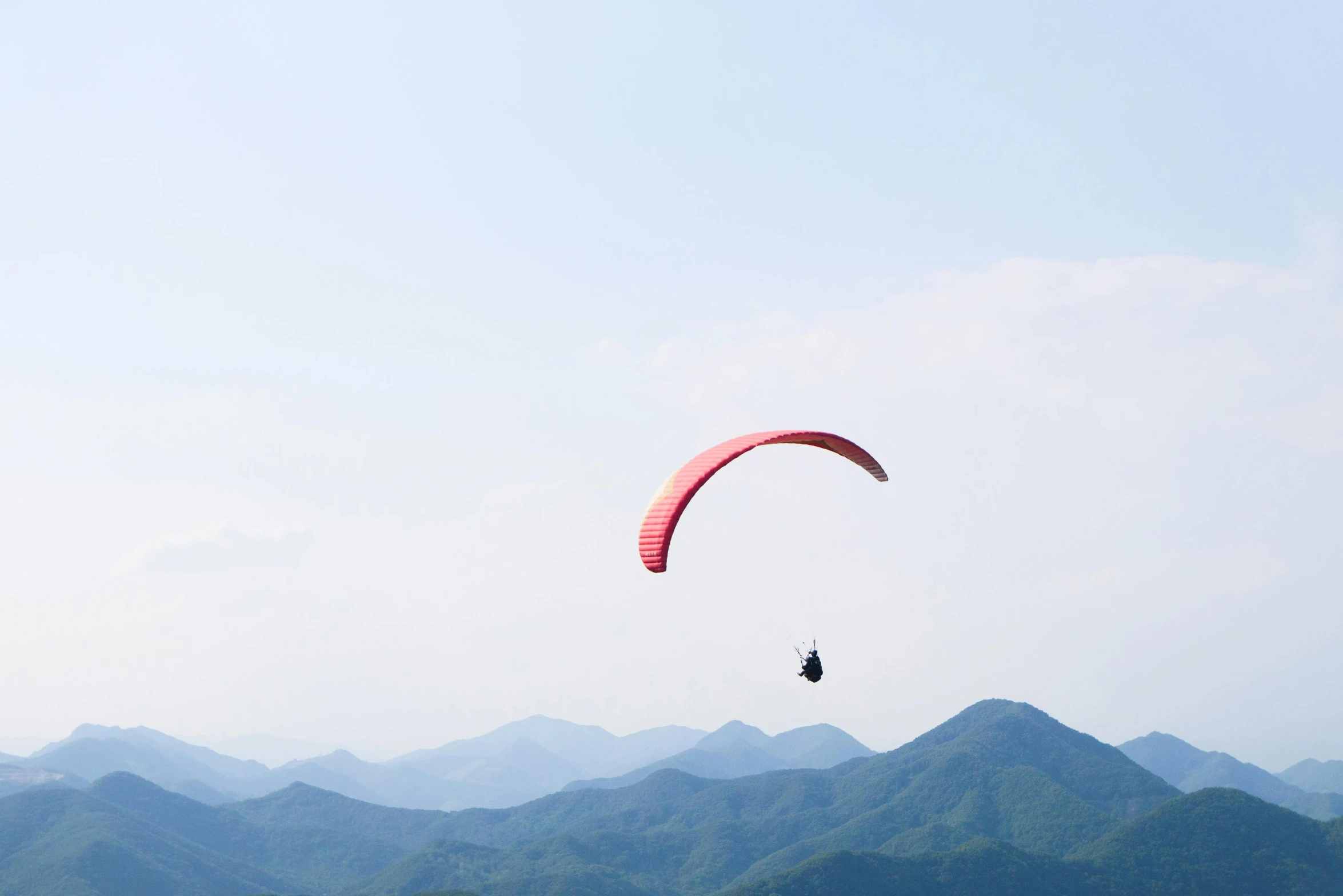 a person para sailing in the ocean with mountains in the background, pexels contest winner, hurufiyya, korean countryside, parachutes, avatar image, 9 9 designs