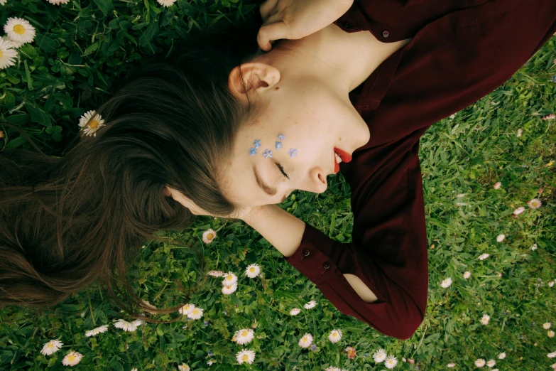 a woman laying in the grass with her eyes closed, inspired by Elsa Bleda, trending on pexels, markings on her face, declan mckenna, portrait sophie mudd, with stars