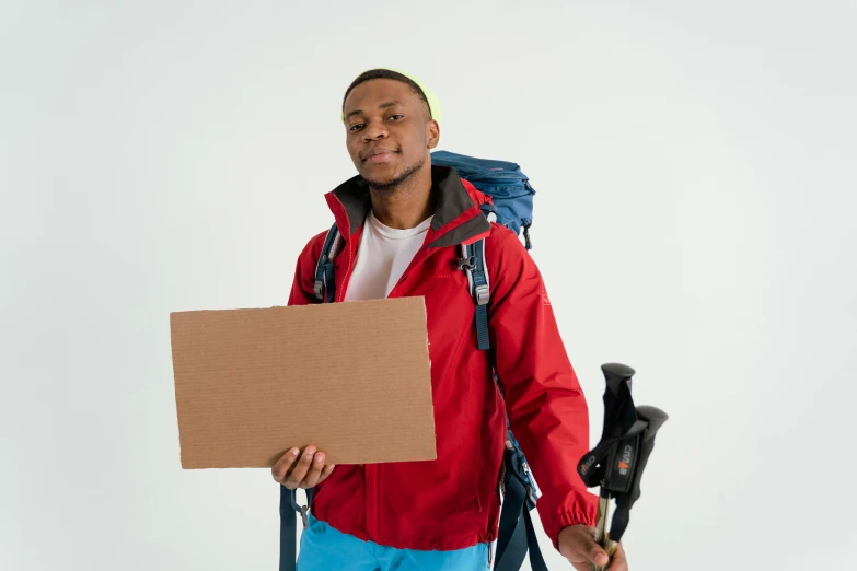 a man in a red jacket holding a sign, pexels contest winner, wearing adventure gear, ( ( brown skin ) ), delivering parsel box, background image