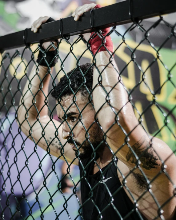 a man holding onto a chain link fence, pexels contest winner, kickboxer fighter, lgbt, sayem reza, cages