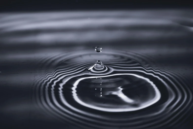 a black and white photo of a drop of water, unsplash, rippling electromagnetic, paul barson, illustration, low - angle shot