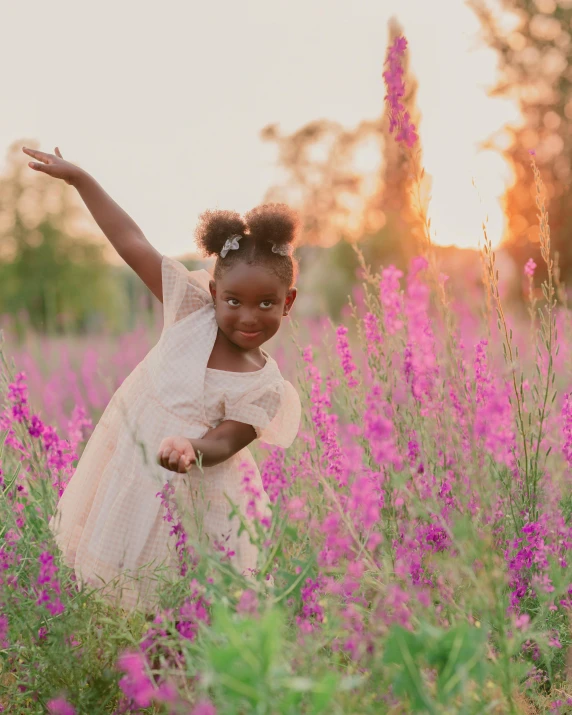 a little girl standing in a field of flowers, by Arabella Rankin, pexels contest winner, color field, photo of a black woman, she is dancing, soft evening lighting, pink and purple