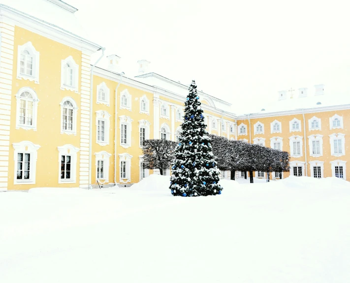 a large yellow building with a christmas tree in front of it, inspired by Illarion Pryanishnikov, pexels contest winner, rococo, white, school courtyard, finland, cold color