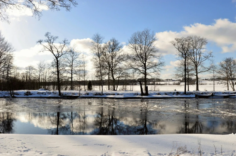 a body of water surrounded by trees covered in snow, a photo, by Jan Tengnagel, hurufiyya, historical setting, thumbnail, beautiful day, cut