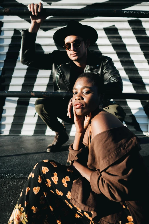 a man and a woman sitting next to each other, a portrait, trending on unsplash, visual art, leather clothing, maria borges, confident pose, shades