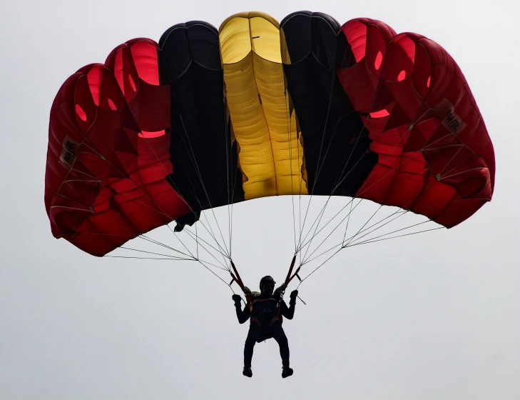 a person that is in the air with a parachute, by Daren Bader, pexels contest winner, hurufiyya, black and yellow and red scheme, covered!, fully functional, instagram post